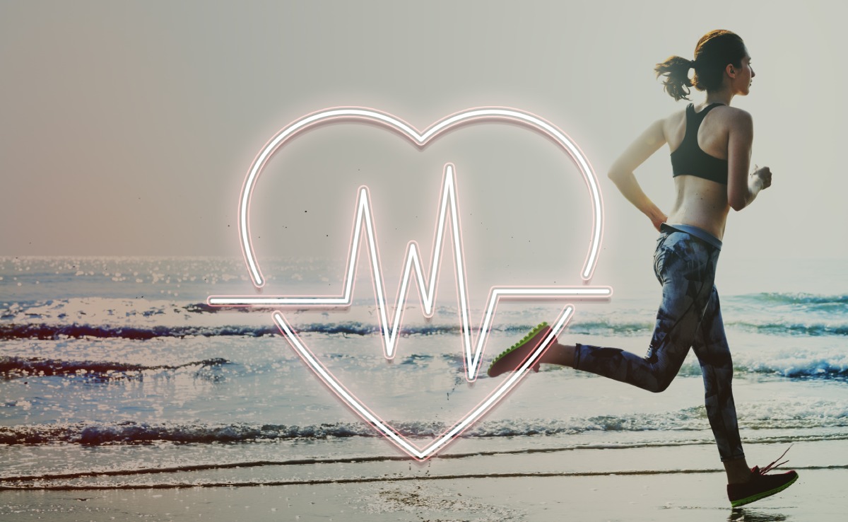 Person running on a beach with a neon heart and heartbeat line overlay in the foreground.