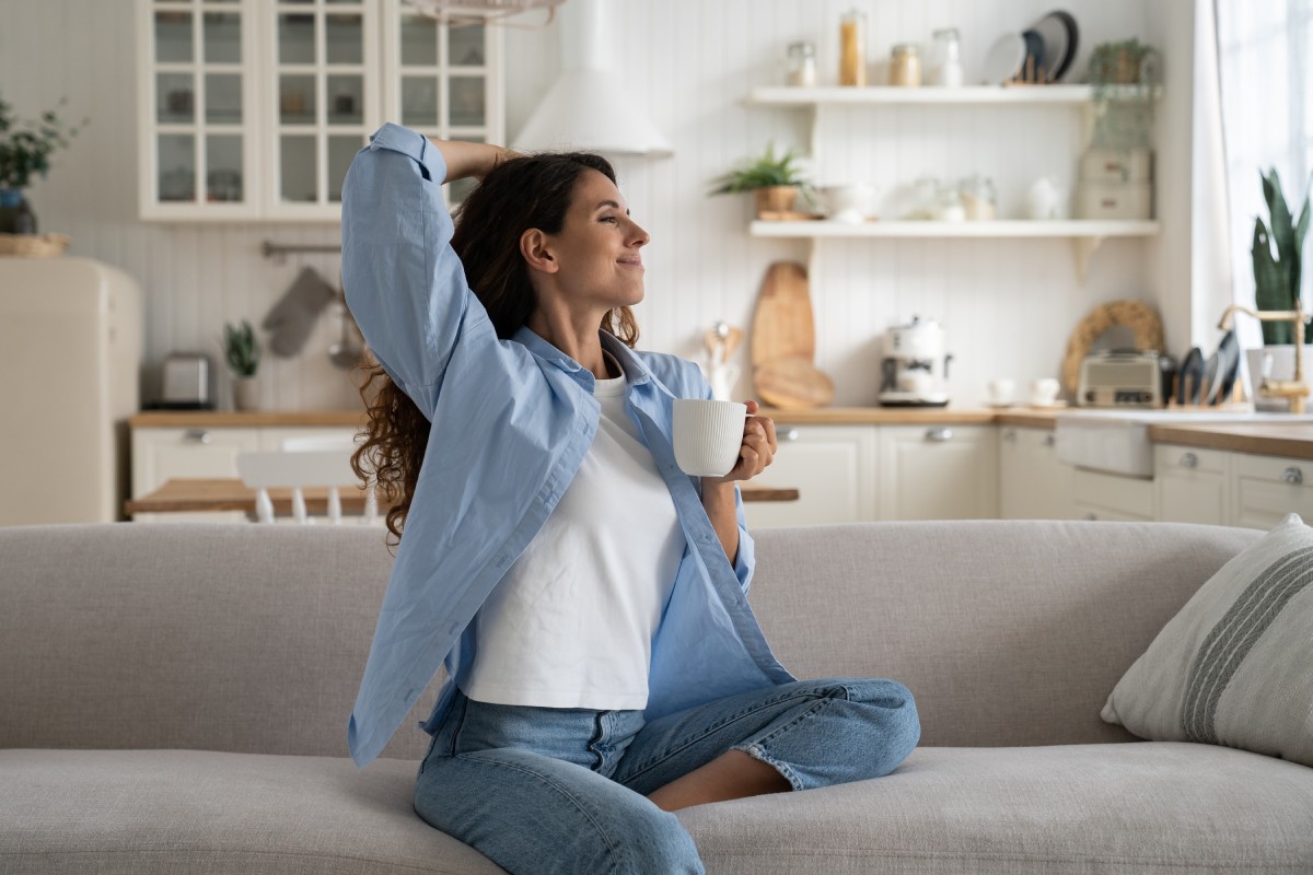 smiling female sitting on couch with favorite drink, relax