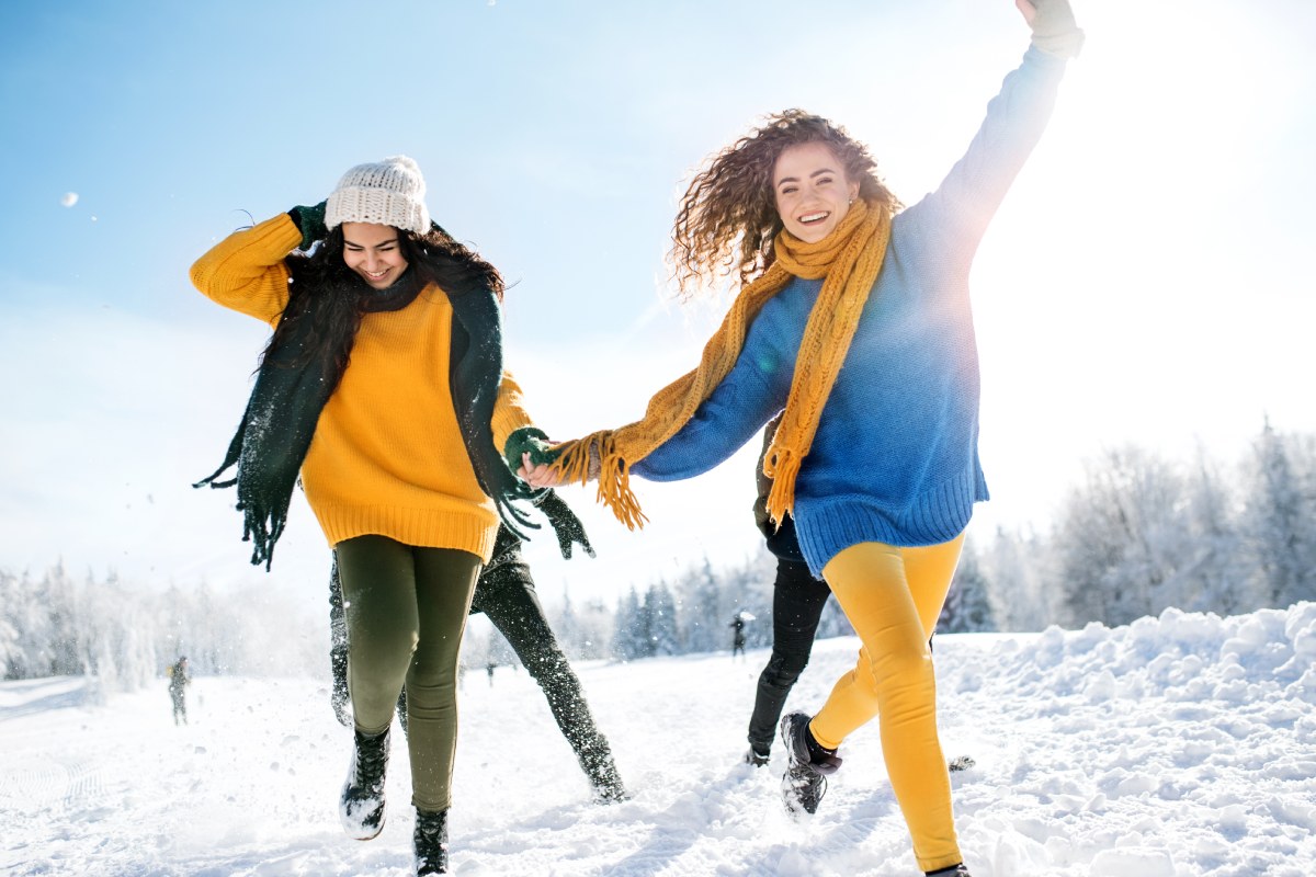 friends on a walk outdoors in snow in winter forest, running
