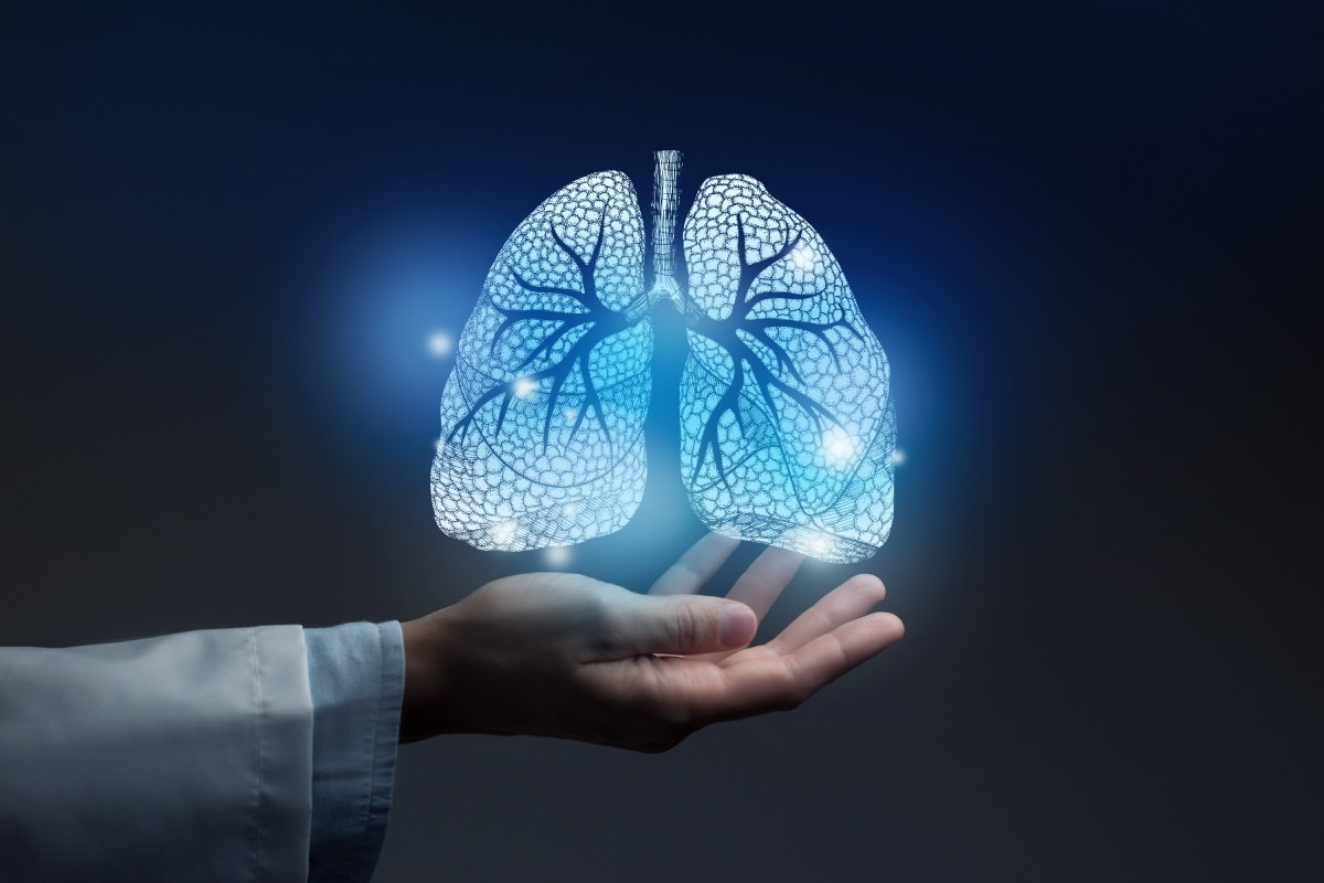 A glowing, digital representation of human lungs hovers above an open hand against a dark background.