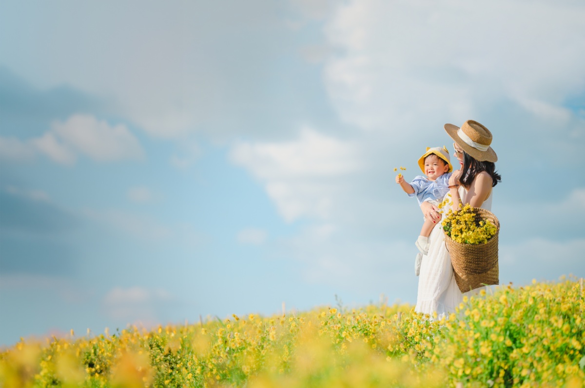 Mother with little child in flower blooming garden.