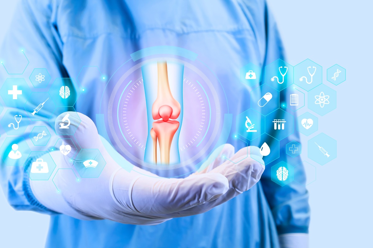 A healthcare professional in blue scrubs and gloves holds a virtual image of a knee joint surrounded by medical icons, representing orthopedics and joint health.