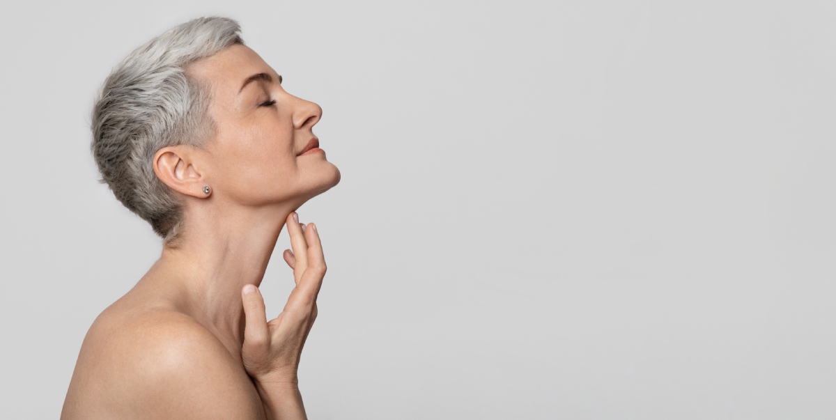 Profile of beautiful middle-aged woman touching soft skin on her neck