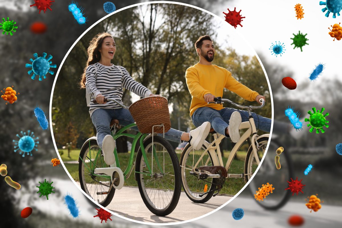 Two people are riding bicycles in a park. The image is encircled and surrounded by illustrations of various bacteria and viruses.