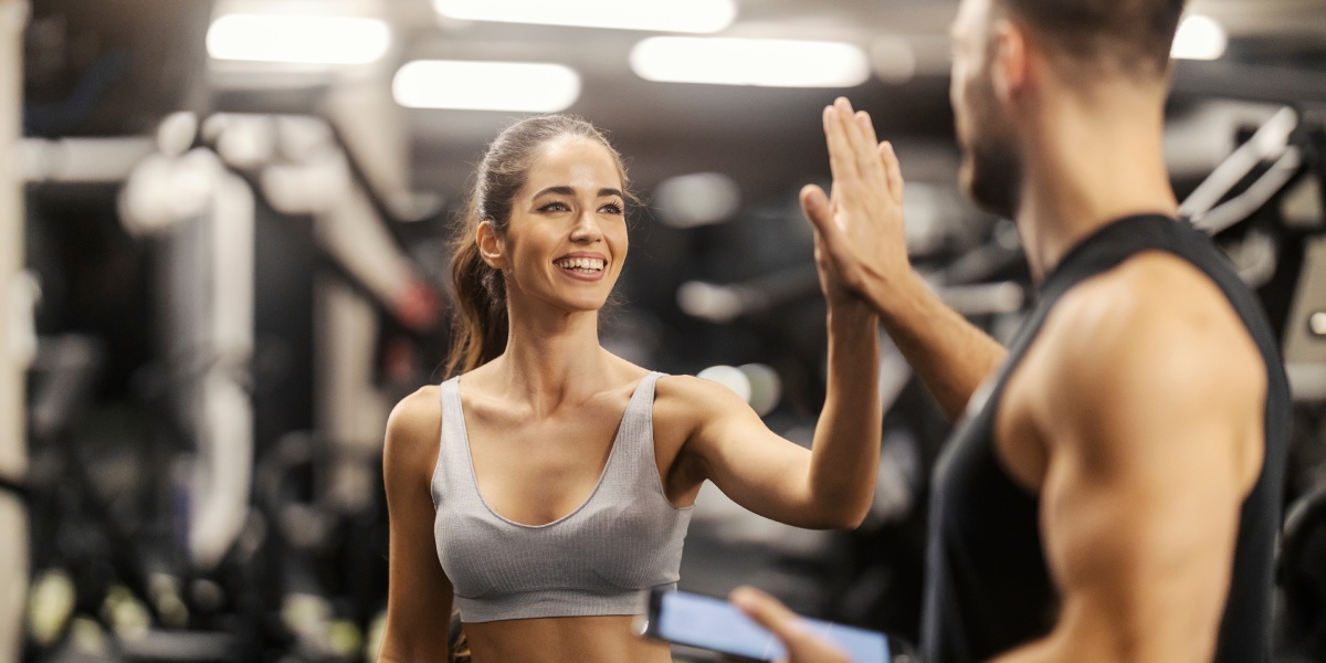fit sportswoman giving high five to her fitness instructor at gym