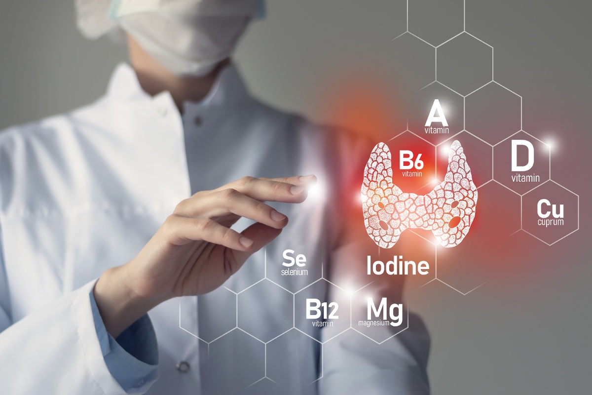 A doctor points at a glowing thyroid illustration with various nutrients like vitamin A, B6, D, iodine, and magnesium labeled around it, emphasizing their importance for thyroid health.