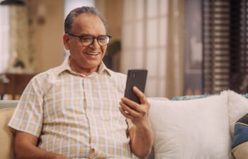 Elderly Indian Man Using Phone for Video Call, Smiling and Happy: Talking with Old Friends and Sharing Life Updates. Cherishing Meaningful Conversations and Laughter with Family Remotely